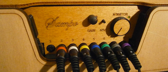 Cajita de música en madera con un botón y una rueda de volumen con varios cables conectados a la caja