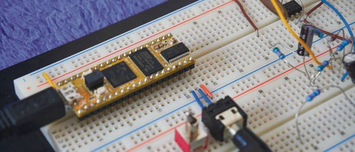 Un circuito en una protoboard de un microcontrolador conectado a unos auriculares, también hay resistencias, condensadores, cables